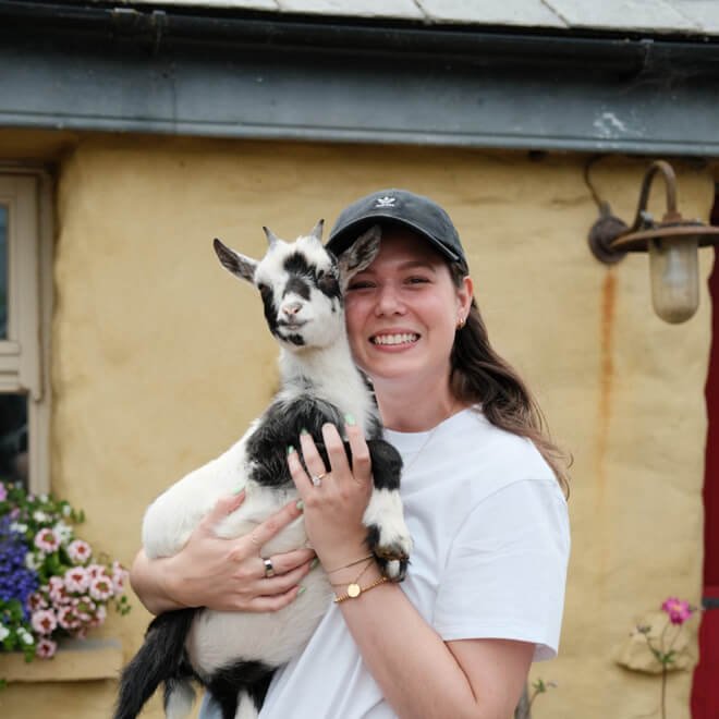 A tour guest holds a baby goat in Ireland