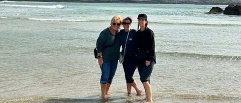 Female tour group having fun in Ireland with their feet in the sea