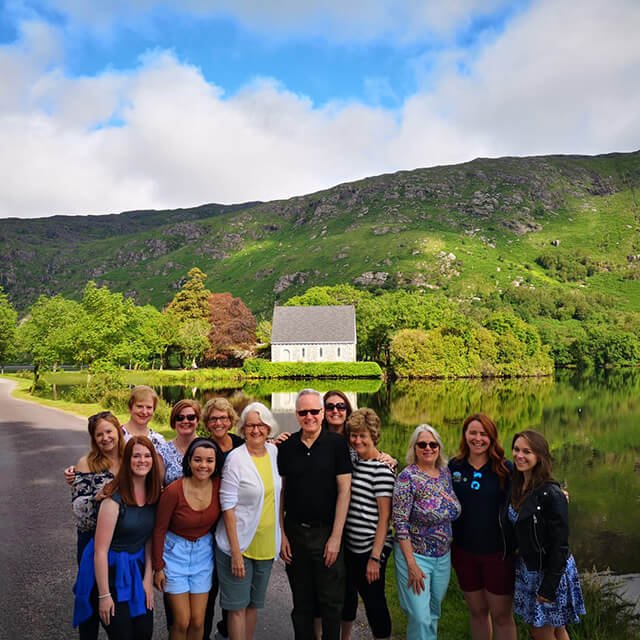 A Diftwood group posing in front of the church at Gougane Barra with a view of the lake and mountains