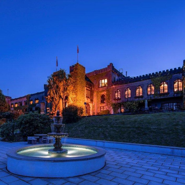 The exterior view of the stunning Abbeyglen Castle Hotel at dusk with water fountain