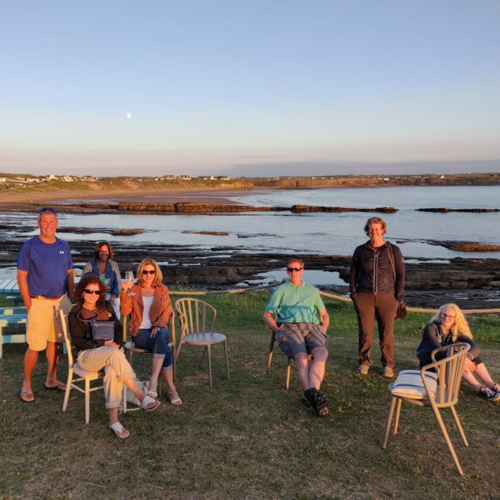 A group sitting on chairs in spanish point outside the armada in the sunset