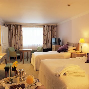 The interior design of a triple room in the Castle Hotel with a breakfast displayed also in the room 