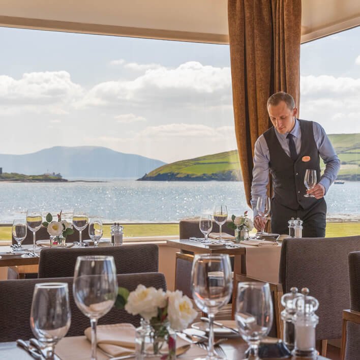 Waiter and dining room with scenic view at Dingle Skellig Hotel in Ireland