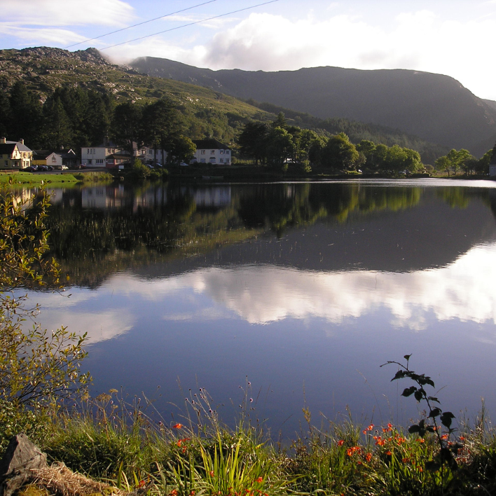 A view of gougane barra hotel from across the lake among trees