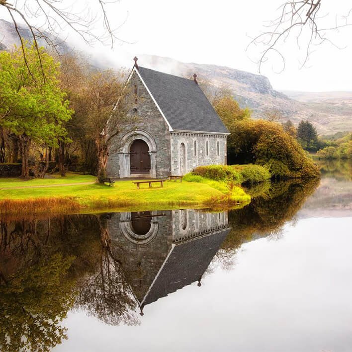 A stunning view of the Gougane Barra Chapel on the Lake with mountains in the background