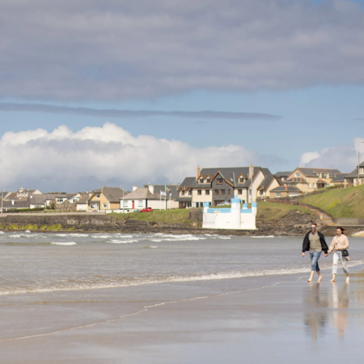 Two people walking on the beach with a view of the hotel in the background
