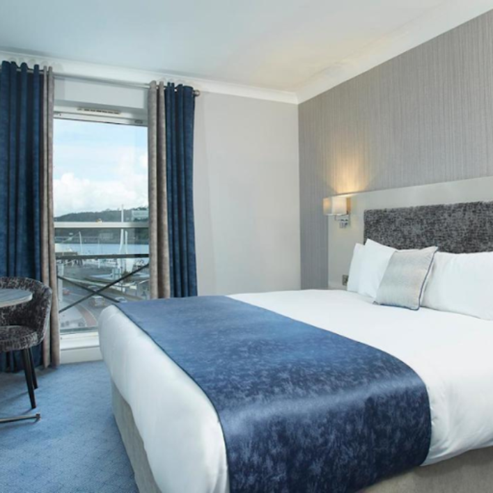 A double bed in the tower hotel with a view through the window of the city