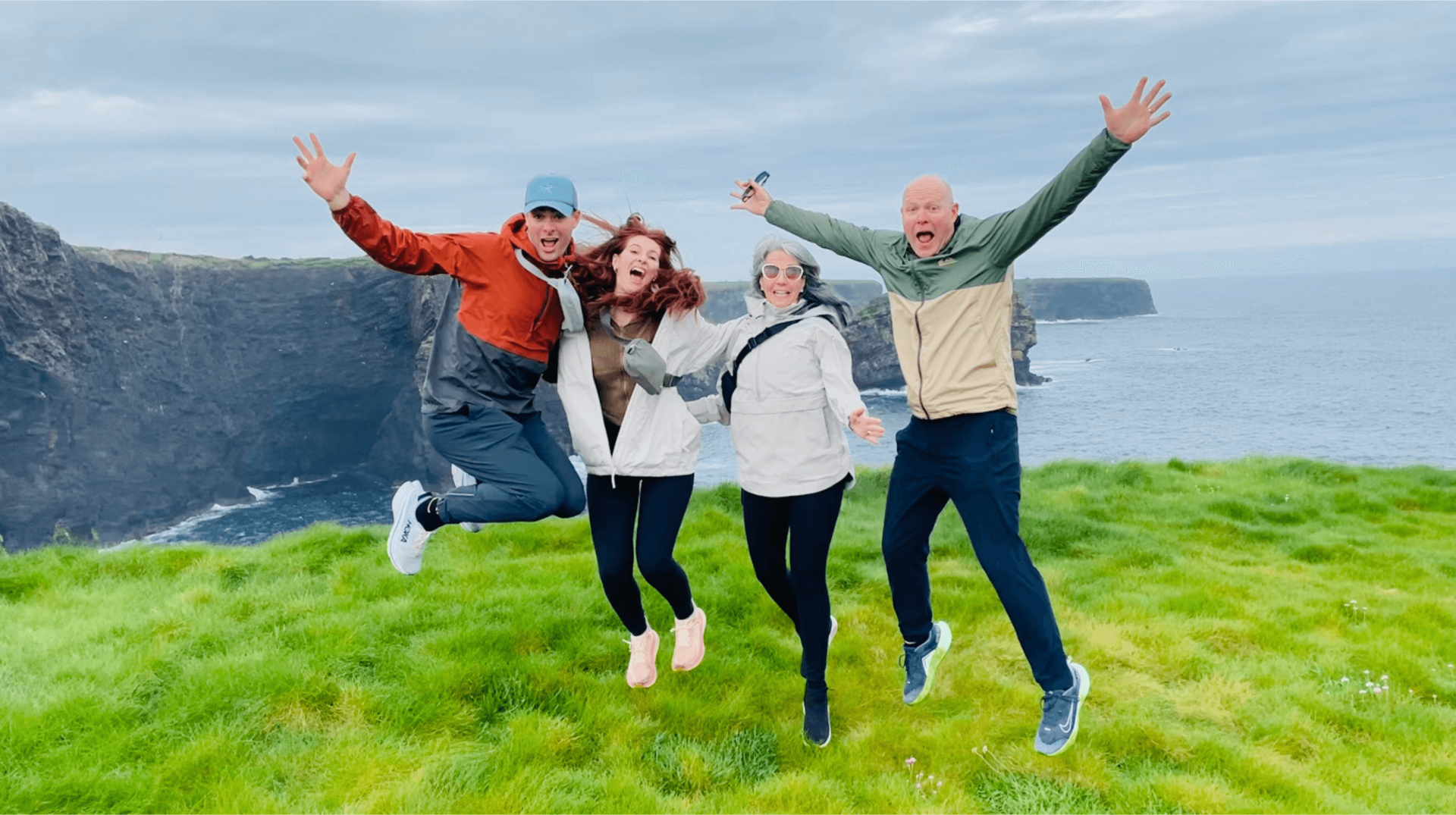 A group of guests jumping and laughing at the cliffs of moher