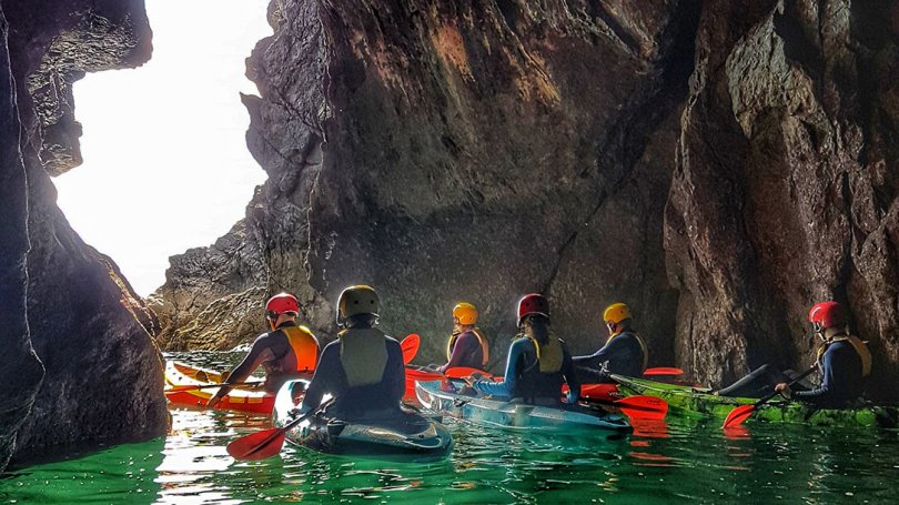 a group of kayakers exploring a sea cave