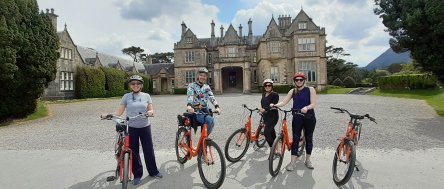 Tour guests biking with old building in Ireland