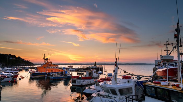 A view of fishing boats in Ballycotton harbour under the sunset