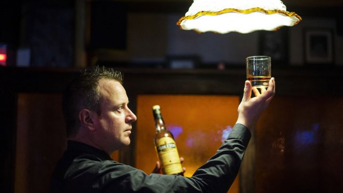 A barman at the Armada Hotel in Ireland examines a measure of Midleton Irish whiskey in a glass tumbler with light shining above him