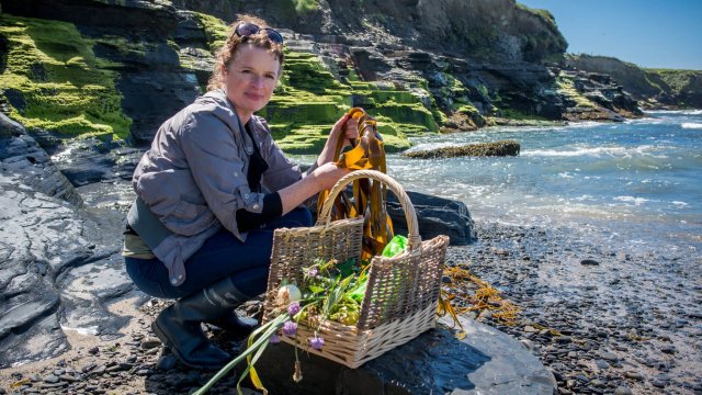 Oonagh Dwyer poses at a coastal location with a selection of foraged food including seaweed