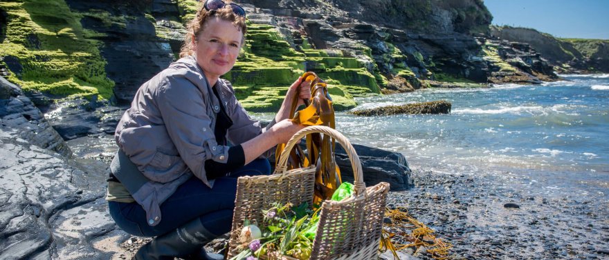 Oonagh Dwyer of Wild Kitchen posing at the coast with a basket of foraged seaweed