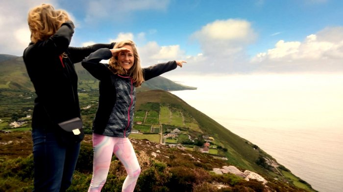 Two tour guests pointing out to sea while spending 2 weeks in Ireland