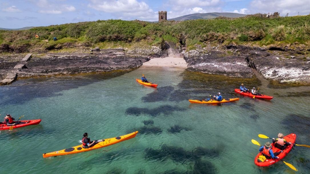 A group of kayakers on dingle bay with husseys folly in the distance