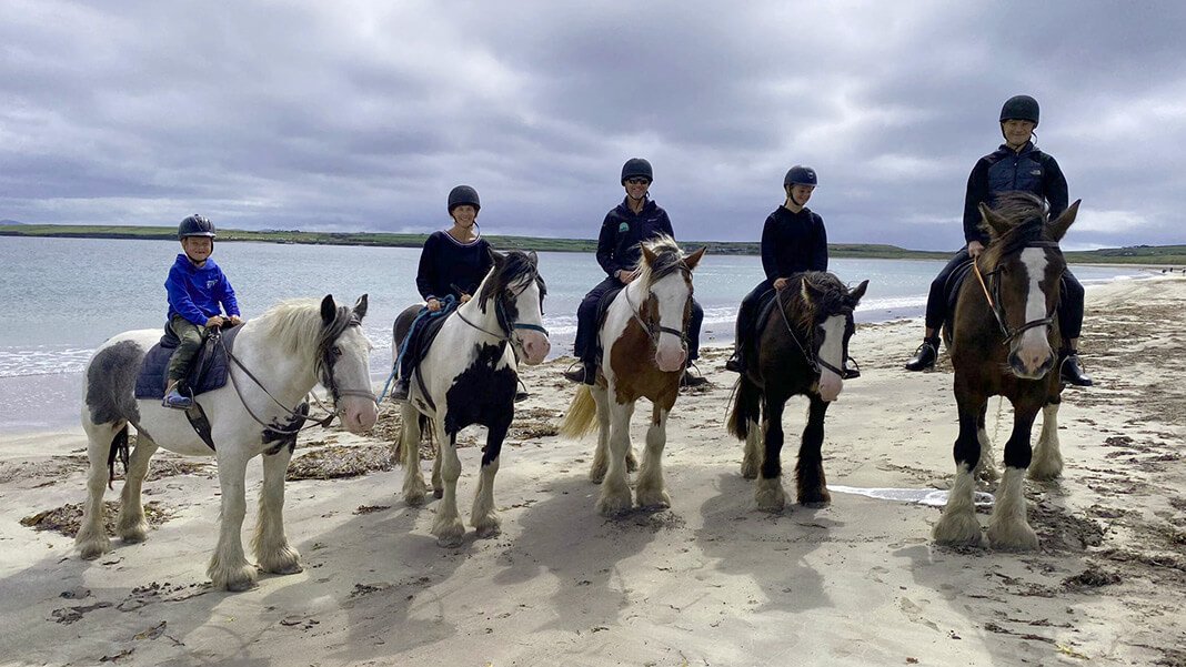 Family riding horses on a beach in Ireland