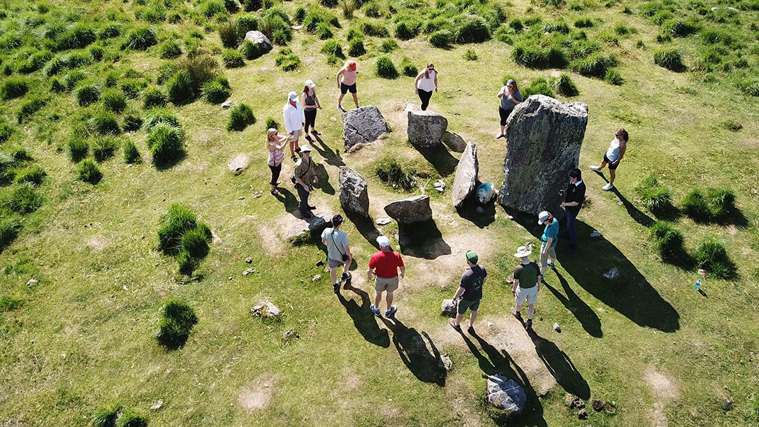 A group of Vagabond guests dancing around in a circle around the Uragh Stone Circle