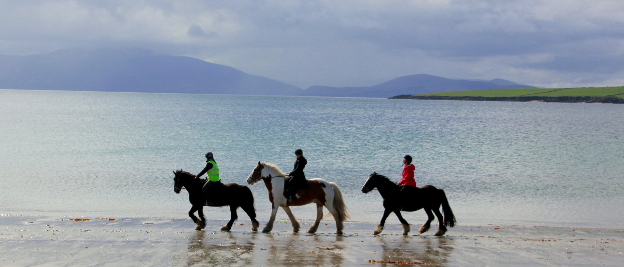 Horseback riders on a scenic beach while on an adventure tour of Ireland