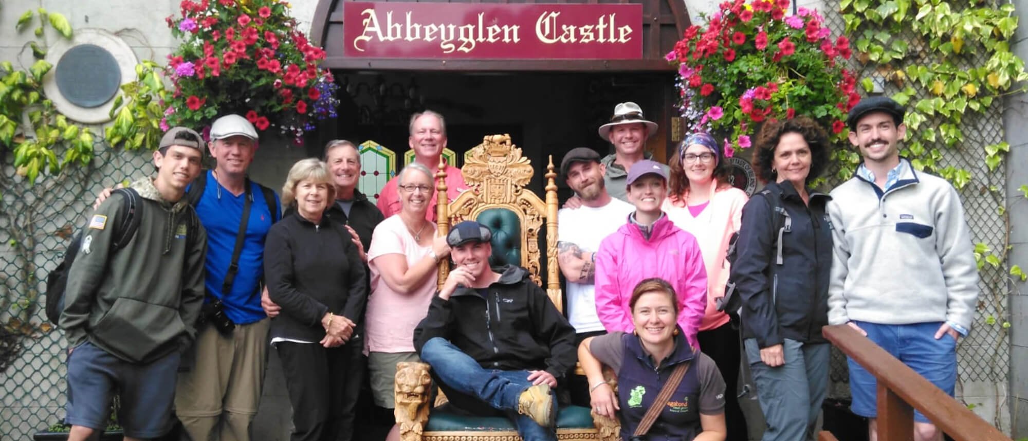 Smiling Vagabond tour group facing the camera outside the Abbeyglen Castle Hotel in Connemara