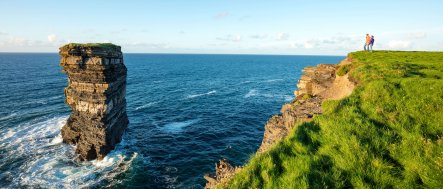 Couple look at Downpatrick Head sea stack from headland in Mayo