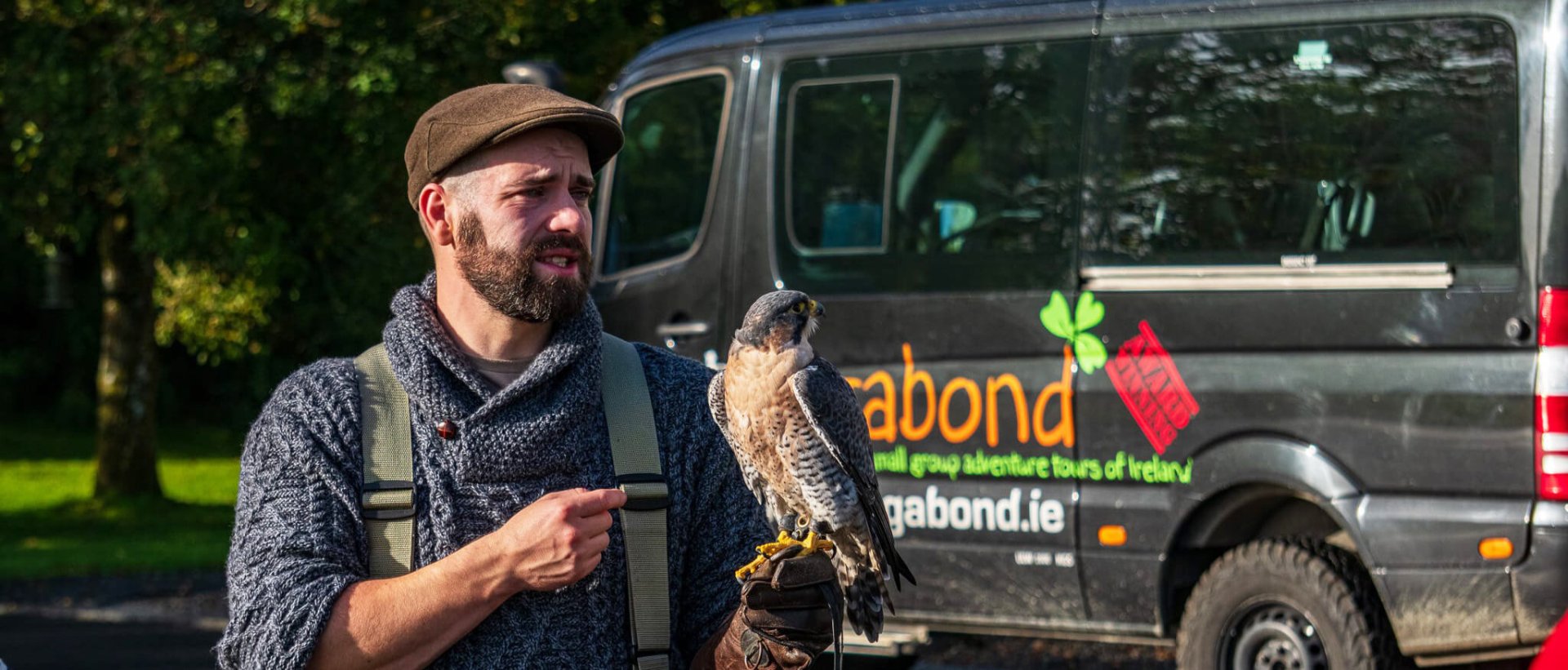 Falconer holding a bird of prey beside a Vagabond tour vehicle