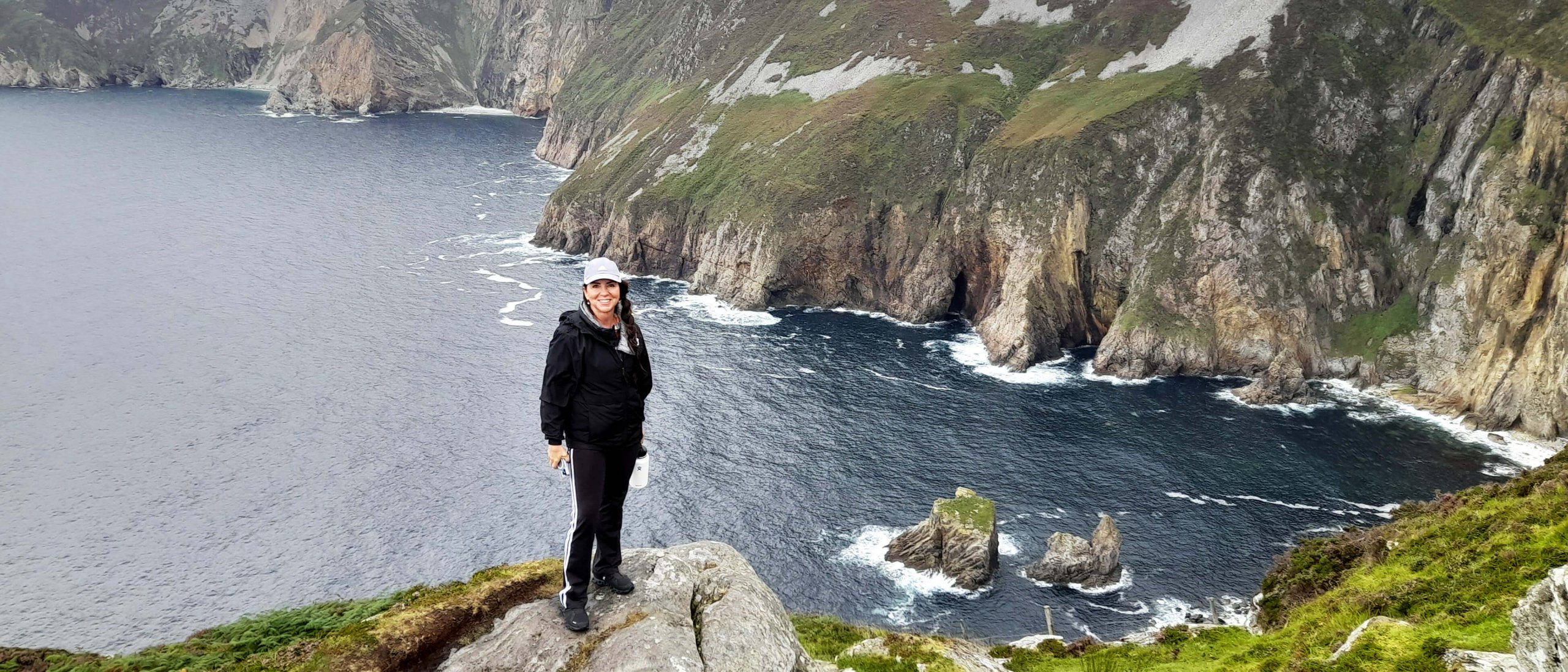 Tour guest poses above sea cliffs in Donegal, Ireland
