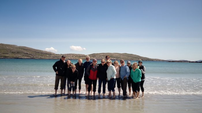 A group of guests standing in the water on derrynane beach posing for a photo