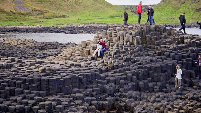 A couple sitting on the stones at the giants causeway taking a selfie