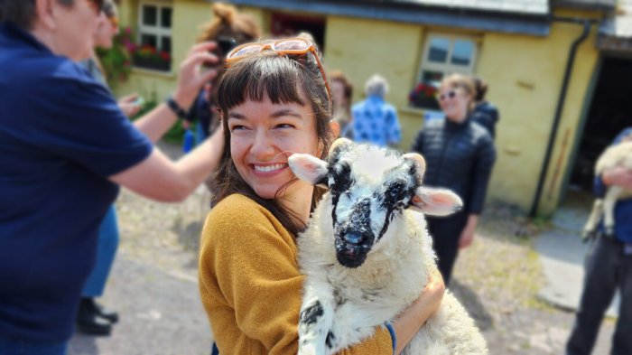 Tour guest holding cute sheep in Ireland