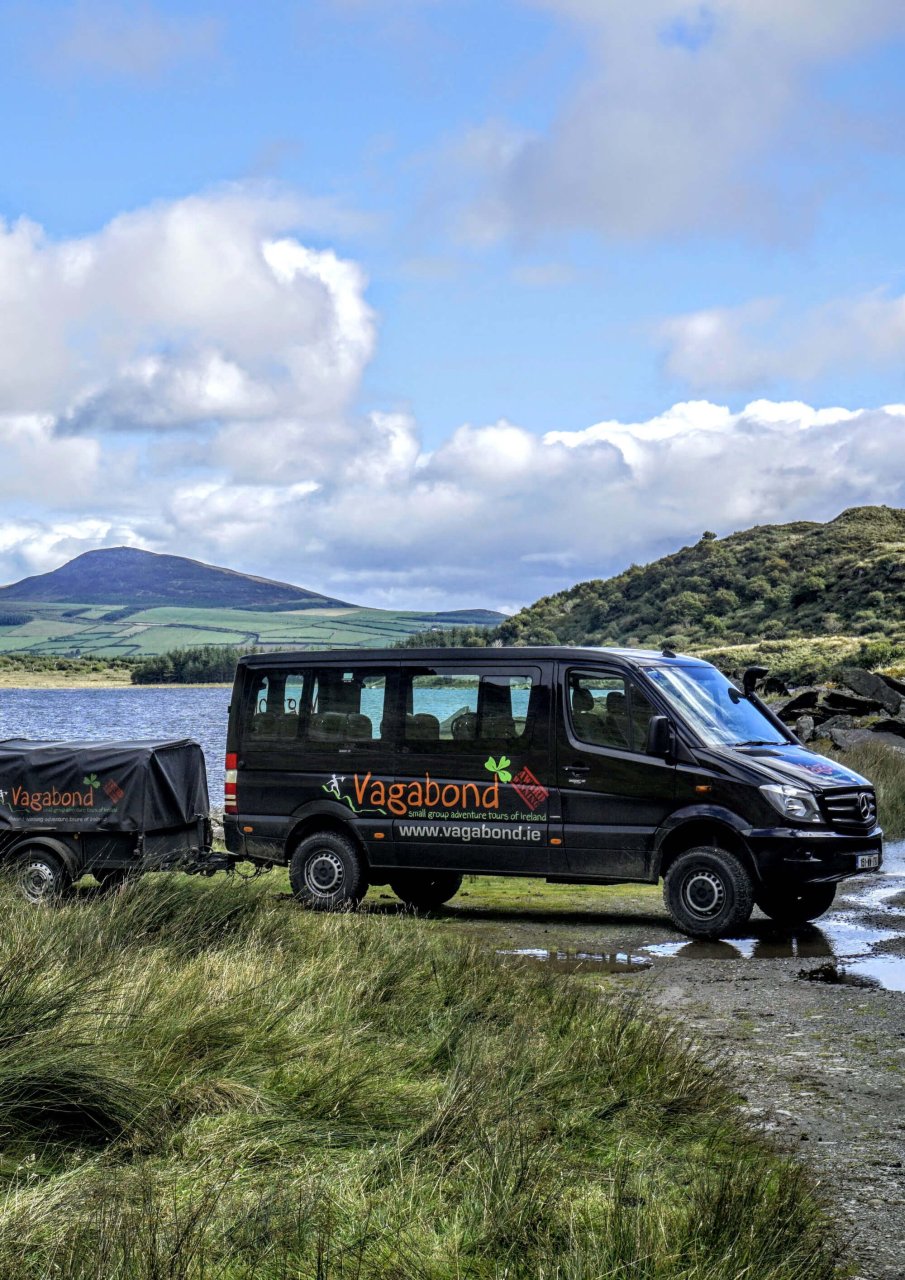 Tour vehicle in scenic green valley beside lake in Ireland