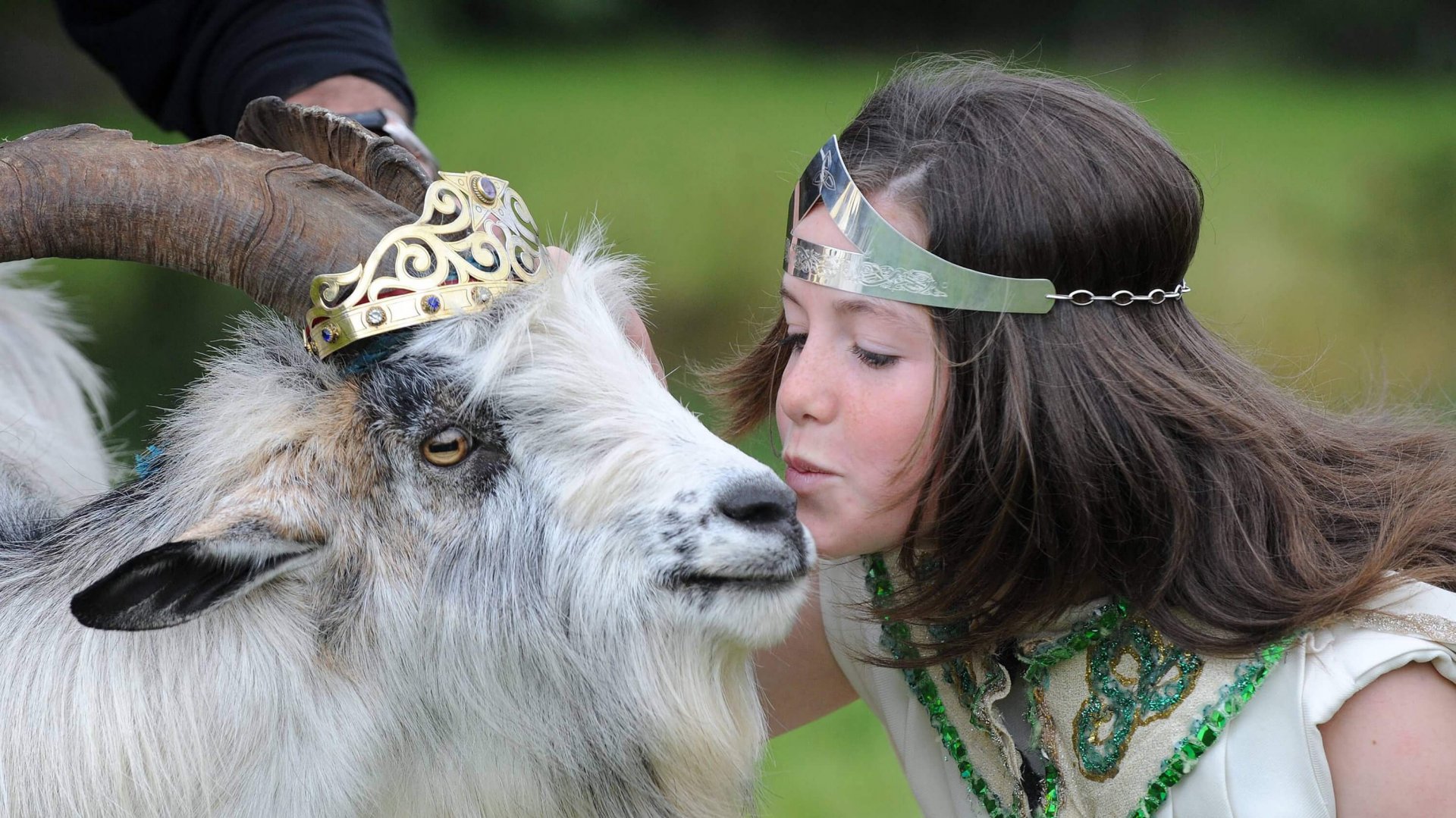A young girl weating a tiara kissing a goat wearing a crown. Nothing weird about this.