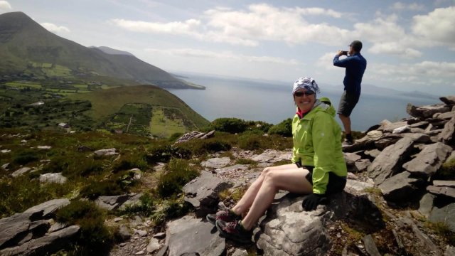 Female hiker and Vagabond tour guest smiles for the camera at the summit of Rossbeigh on the Iveragh peninsula in Kerry, Ireland