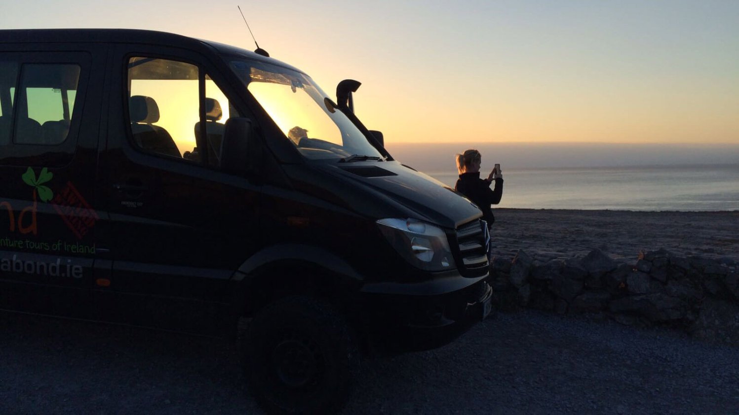 Vagatron tour vehicle with Vagabond tour guide, silhouette by the sun