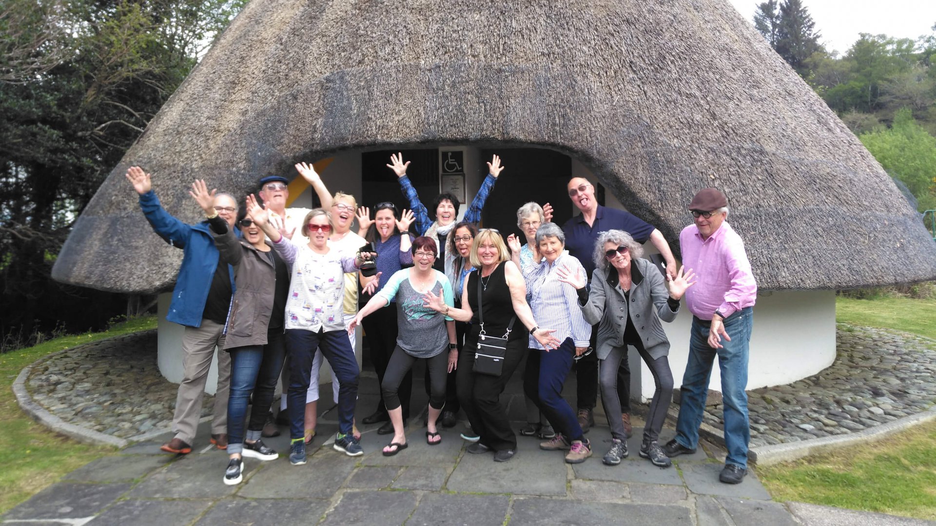 Tour group outside thatched public toilets in Gougane Barra, Ireland
