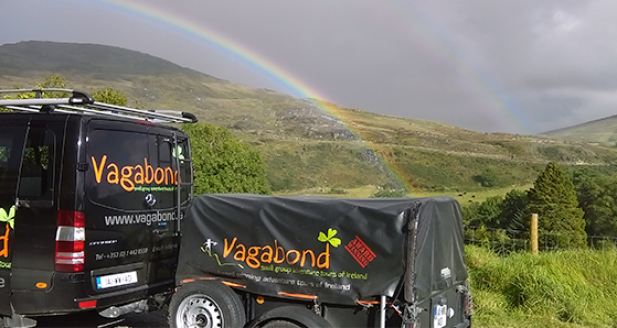 Tour vehicle parked with rainbow in the background