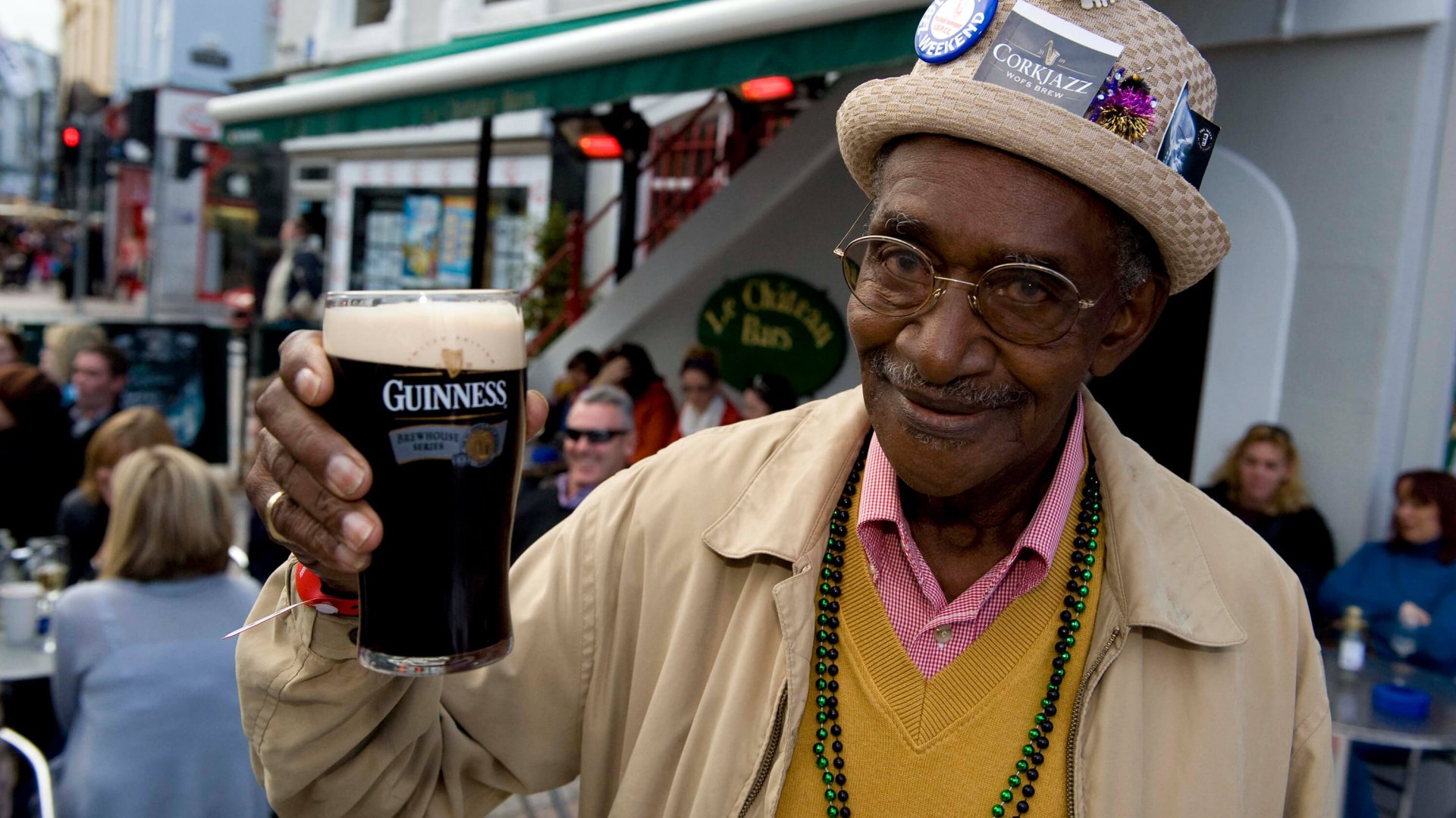 A happy man toasts the camera with a pint of Guinness