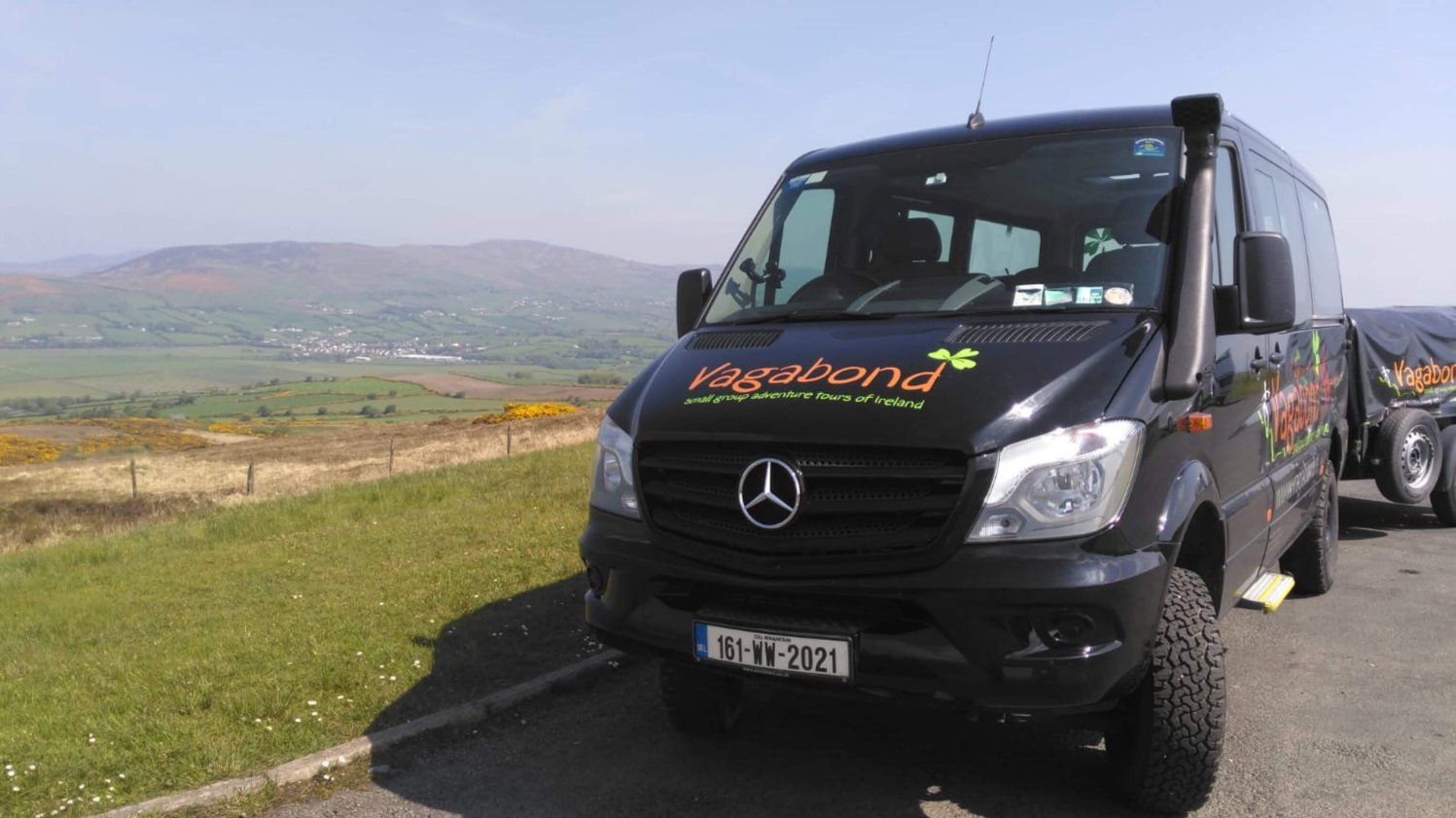 Ein geparkter 4x4 VagaTron-Reisebus mit blauem Himmel und einer schönen irischen Landschaft im Hintergrund