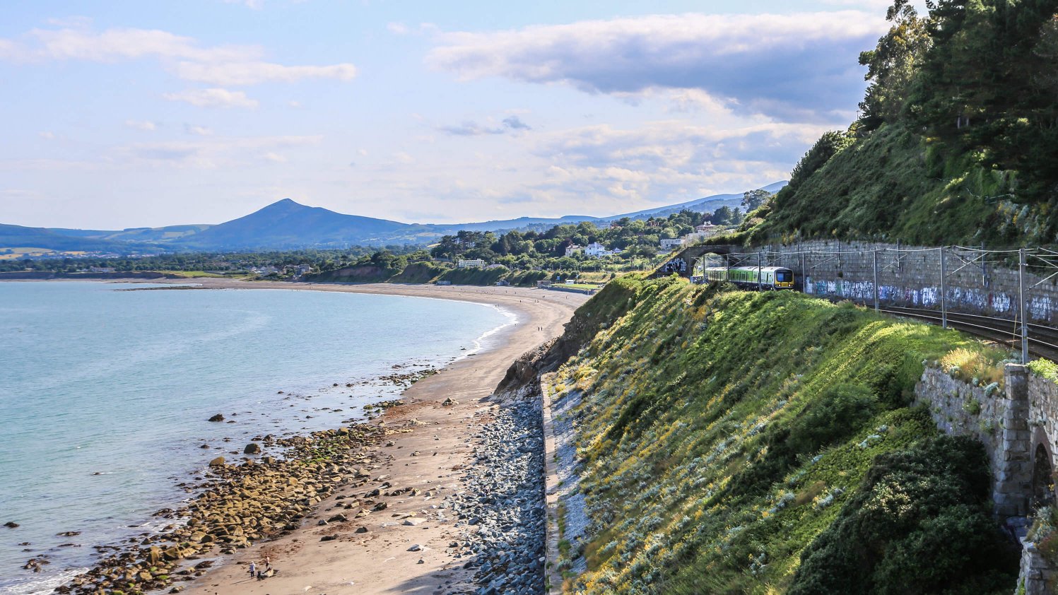 A DART train makes its way along Killiney Bay with the Sugarloaf mountain in the background